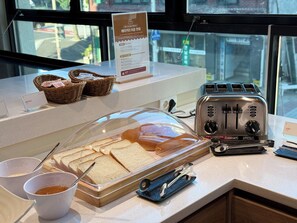 A breakfast counter with a toaster, bread, and condiments.