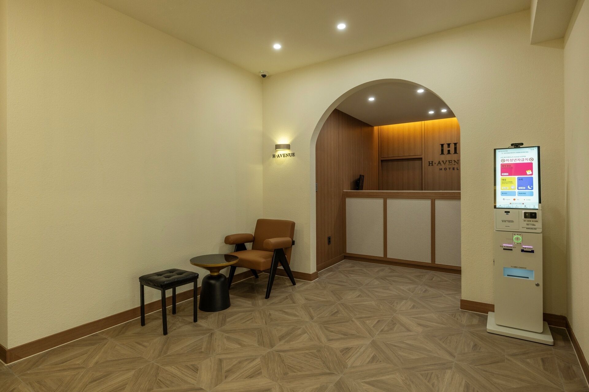 Un vestíbulo de hotel con una recepción, zona de estar y un quiosco de autoservicio.