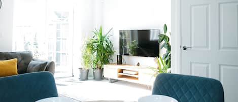 Una sala moderna con sofá, mesa de comedor y plantas en macetas.