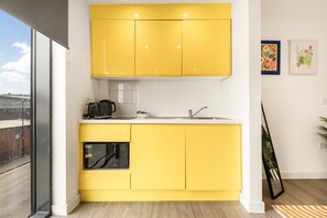 Een moderne keuken met gele kastjes, een ingebouwde magnetron en een koffiezetapparaat.
