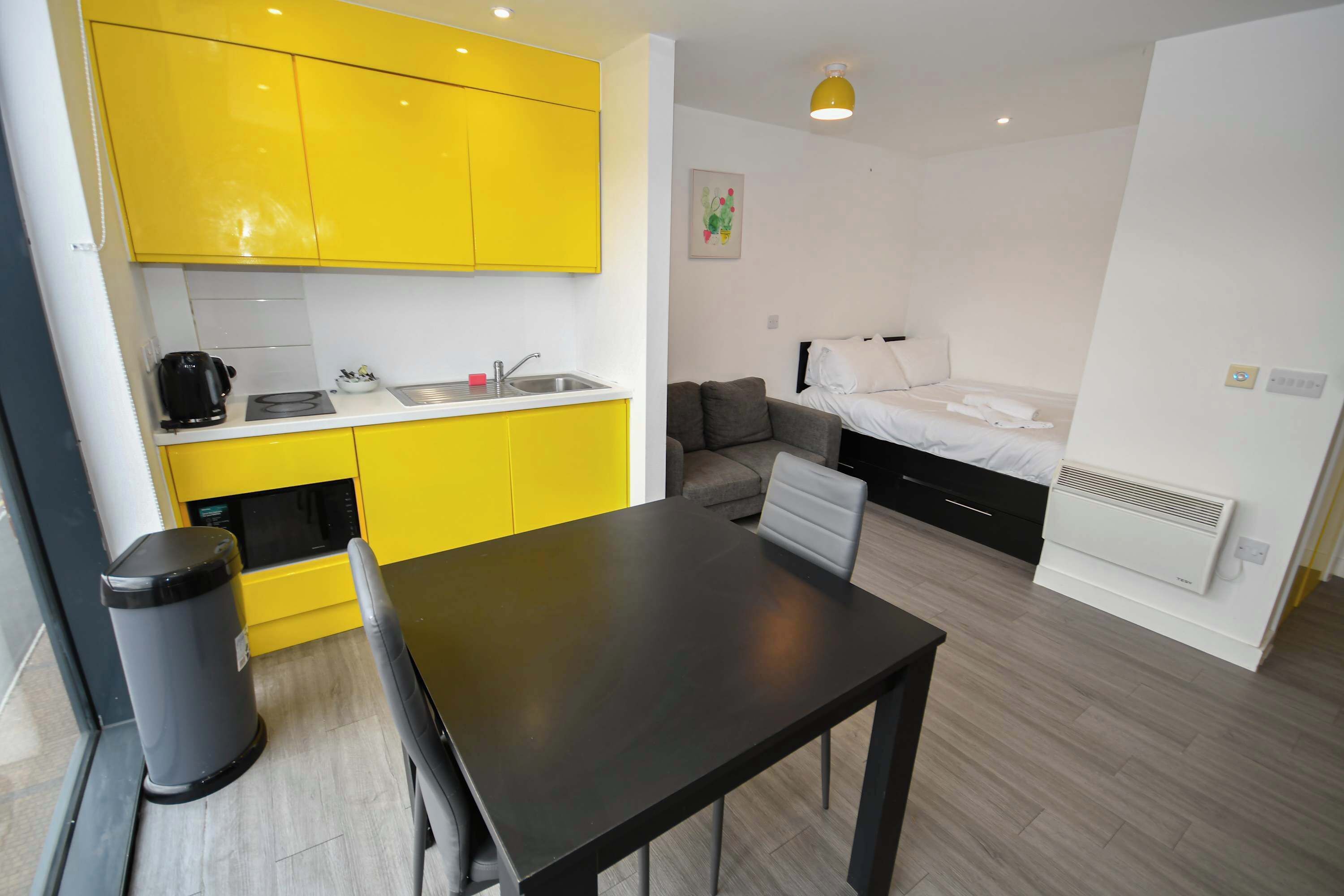 A compact living space with a kitchenette, a dining area, and a bed.