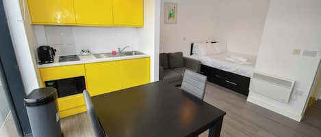 A compact living space with a kitchenette, a dining area, and a bed.