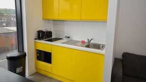 A compact kitchen with yellow cabinets, a stainless steel sink, and a black coffee maker. - Modern & Convenient Studio in Central Sheffield (Sheffield)