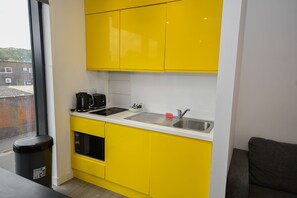 A compact kitchen with yellow cabinets, a stainless steel sink, and a black coffee maker. - Modern & Convenient Studio in Central Sheffield (Sheffield)