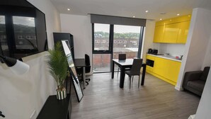 A modern apartment with a dining area, kitchen, and a large window. - Modern & Convenient Studio in Central Sheffield (Sheffield)