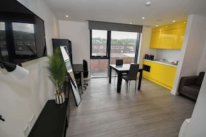 A modern apartment with a dining area, kitchen, and a large window. - Modern & Convenient Studio in Central Sheffield (Sheffield)