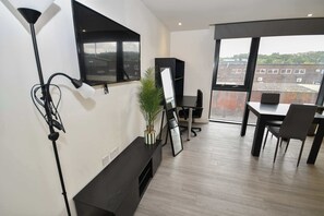 A modern office space with a large window, a desk, chairs, a plant, and a mounted TV. - Modern & Convenient Studio in Central Sheffield (Sheffield)