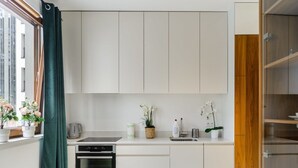 A modern kitchen with white cabinets, a built-in oven, and a window with curtains. - Apartment in Porspoder Near Plage du Bourg (Warsaw)