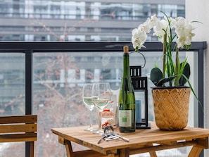 A table with a bottle of wine, two glasses of white wine, a cork, a basket with white flowers, and a set of keys. - Convenient Base in Warsaw City Centre (Warsaw)