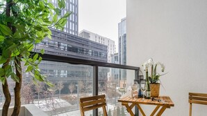 A balcony with a wooden table, two chairs, a potted plant, and a bottle of wine. - Apartment in Porspoder Near Plage du Bourg (Warsaw)