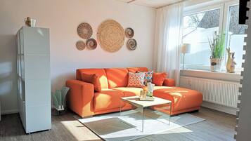 A living room with a sofa, coffee table, and decorative wall hangings.