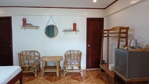 A room with a bed, two wicker chairs, a small table, a television, and a refrigerator. - Kerusso Haven (Puerto Princesa)