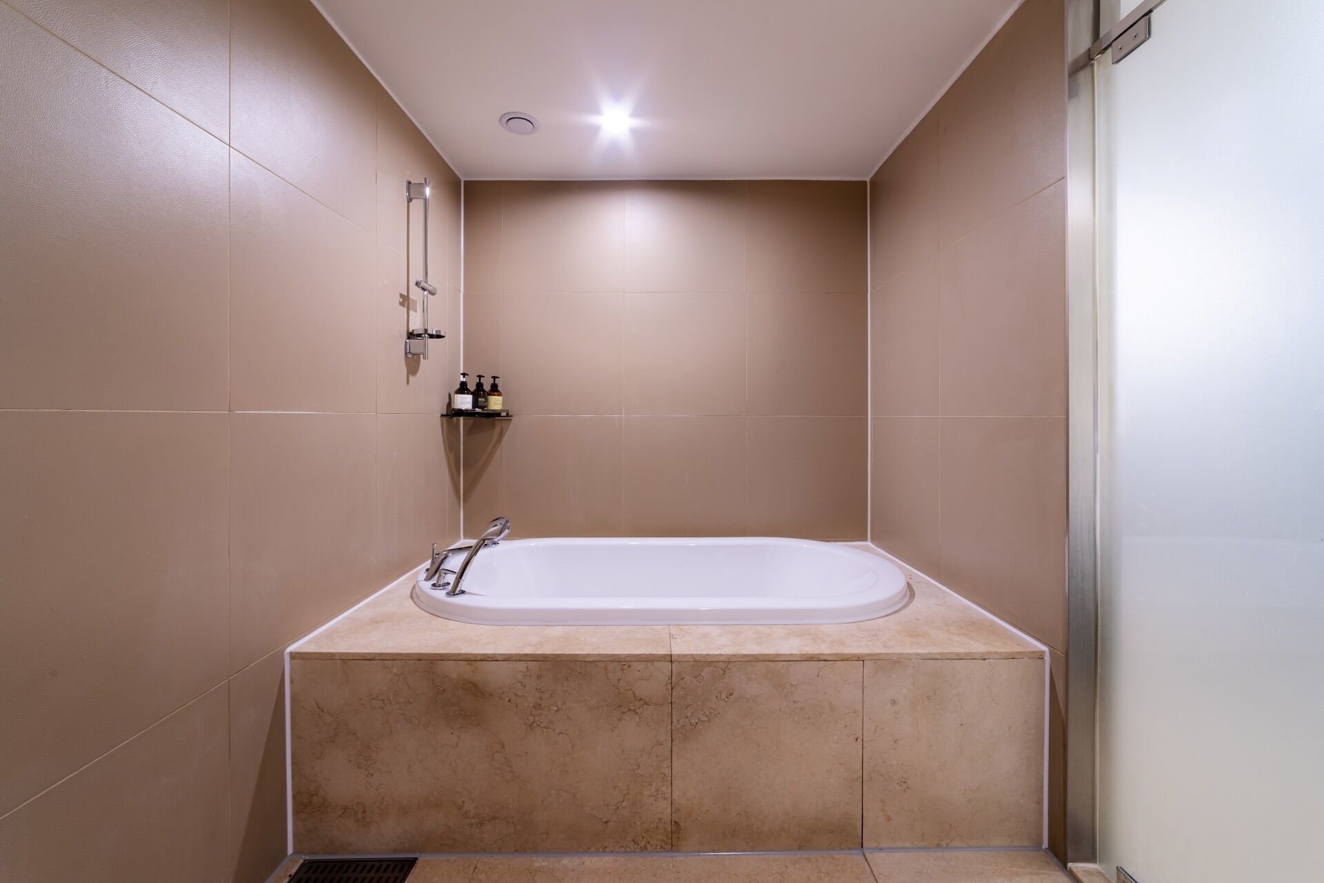 Un baño con bañera, ducha y estante con artículos de aseo.