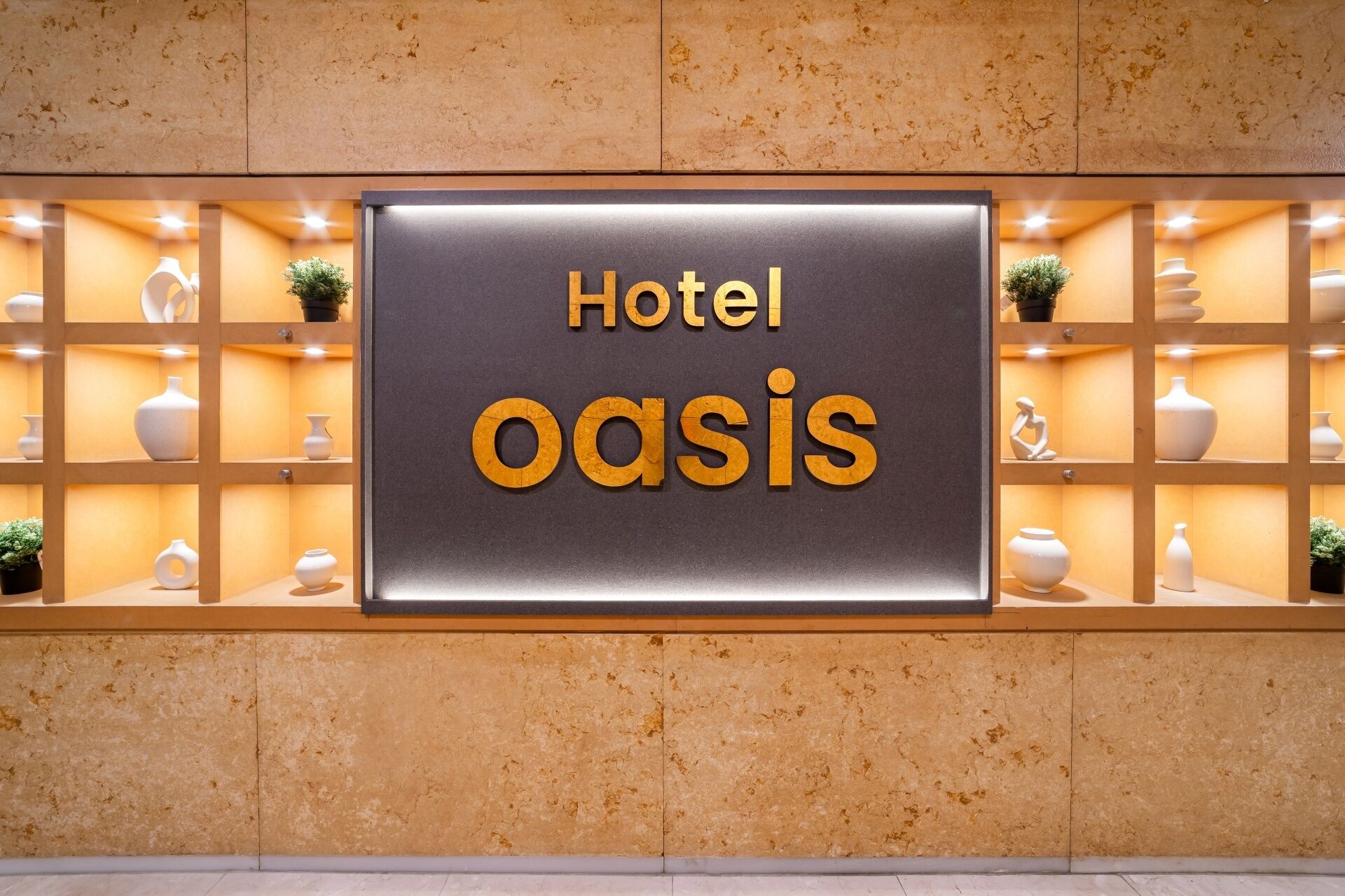 A sign for 'Hotel Oasis' with a modern design, featuring a central signboard and decorative shelves with vases and plants.