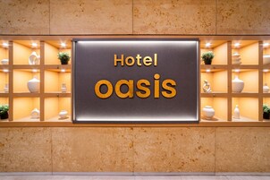 Señal para 'Hotel Oasis' con un diseño moderno, que incluye un cartel central y estantes decorativos con jarrones y plantas.