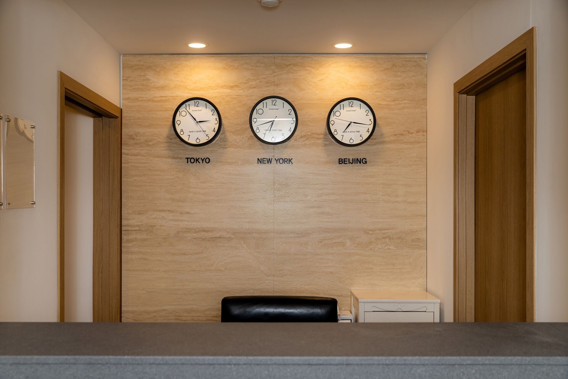 Una mesa de recepción con tres relojes que marcan la hora de Tokio, Nueva York y Pekín.