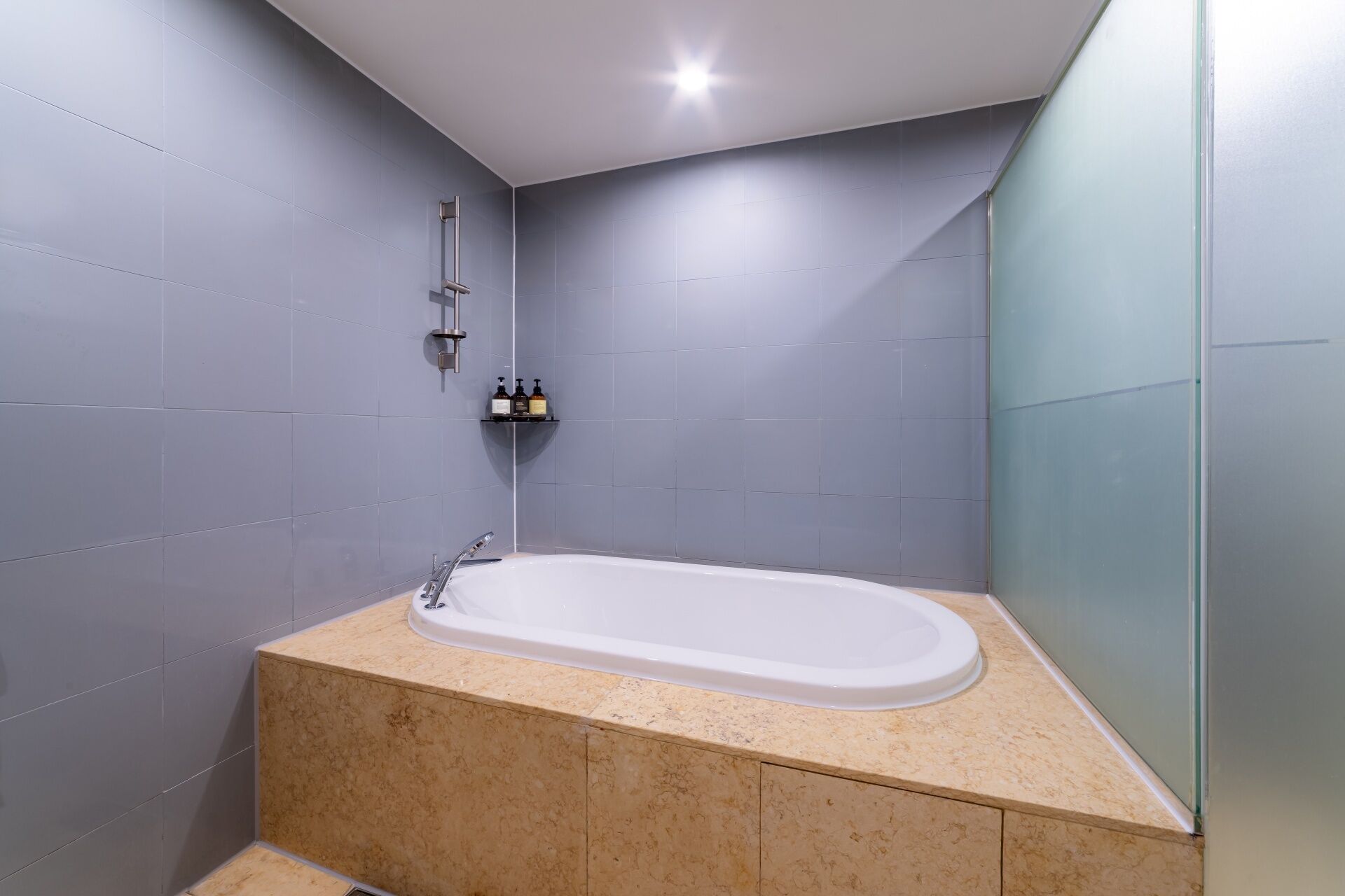 Un baño moderno con una bañera independiente, cabezal de ducha y un estante con artículos de aseo.