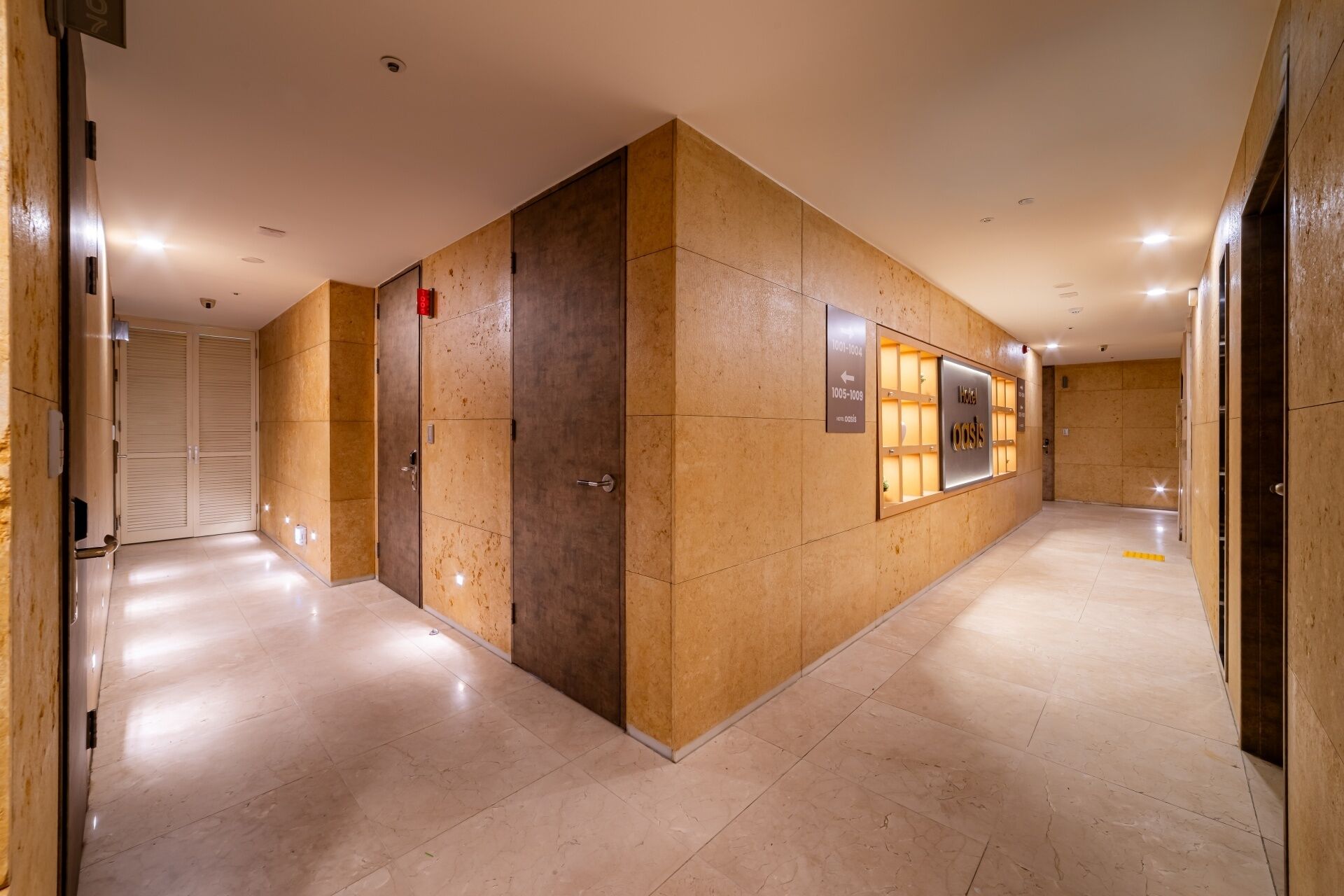 Um hall de hotel com design moderno, apresentando uma mesa de recepção, um quadro de informações fixado na parede e um piso de azulejos impecável.