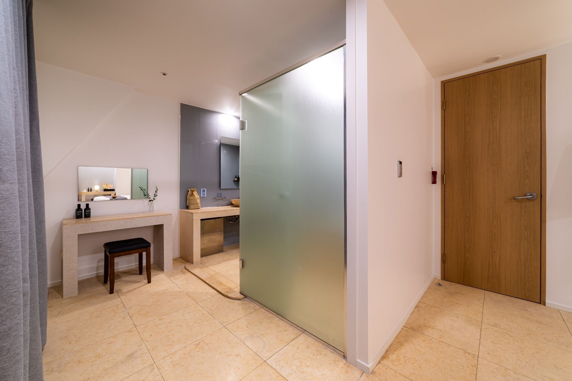 A modern bathroom with a vanity, mirror, and a sliding door leading to another room.