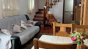 Ein Wohnzimmer mit einer Couch, einem Holztisch mit Stühlen, einer Treppe und einem Spiegel.