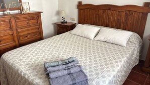 Ein Schlafzimmer mit Bett, Holz-Kopfstück, einem Schminktisch, einem Nachttisch, einem Spiegel und einer Chandelier.