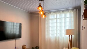 Moderni olohuone, jossa on litteänäyttöinen televisio, sohva, sohvapöytä ja lamppu.