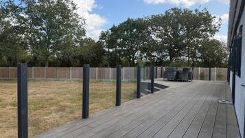 A deck with a wooden floor and black posts, a fenced yard, and a building with a white exterior.