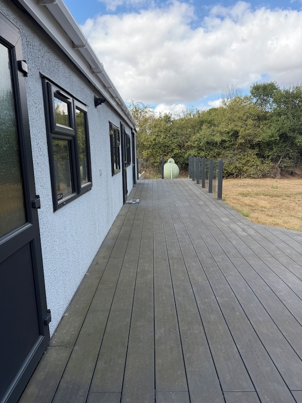 A wooden deck leading to a building with a white exterior and black window frames.