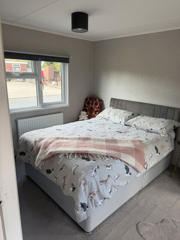 A bedroom with a bed, a window, a radiator, and a teddy bear.