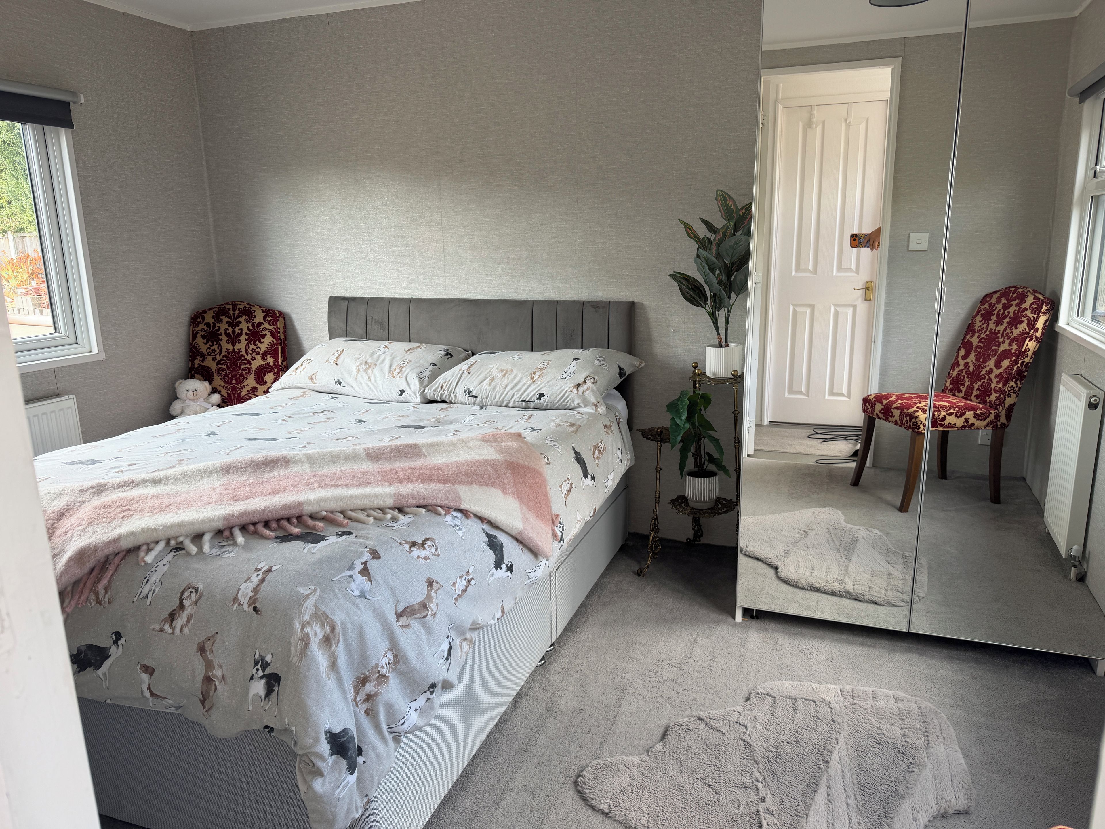 Un dormitorio con cama, una silla, un espejo y una planta en maceta.