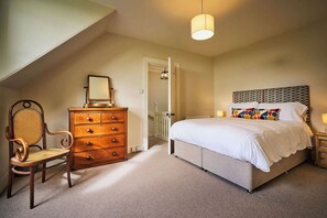 Ein Schlafzimmer mit Bett, Schminktisch, Stuhl und einer Pendelleuchte.