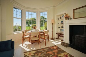 A dining area with a table set for four, a fireplace, and a view of the outdoors. - Kinclune House & Buildings on Private Angus Estate (Kirkton of Kingoldrum)