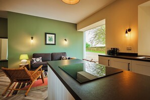 A modern kitchen with a large island, a dining area with a sofa, and a view of the outdoors. - Kinclune House & Buildings on Private Angus Estate (Kirkton of Kingoldrum)