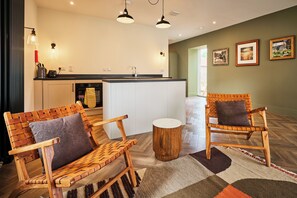 A modern kitchen with white cabinets, a black countertop, and a wooden dining table with chairs. There are two pendant lights above the table. - Kinclune House & Buildings on Private Angus Estate (Kirkton of Kingoldrum)