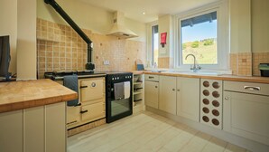 A kitchen with a stove, oven, sink, and window with a view. - Peaceful Farmhouse, Kinclune Estate, Angus Glens (Kirkton of Kingoldrum)