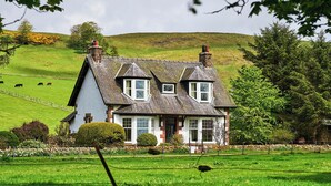 A two-story house with a steeply pitched roof, dormer windows, and a visible chimney. - Peaceful Farmhouse, Kinclune Estate, Angus Glens (Kirkton of Kingoldrum)