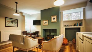 A cozy living room with a fireplace, wooden furniture, and a bookshelf. - Osprey Annex family suite at Kinclune Estate, Angus (Kirkton of Kingoldrum)