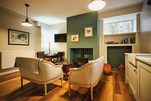 A cozy living room with a fireplace, wooden furniture, and a bookshelf. - Osprey Annex family suite at Kinclune Estate, Angus (Kirkton of Kingoldrum)