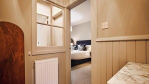 A room with a bed, a radiator, and a wooden door. - Osprey Annex family suite at Kinclune Estate, Angus (Kirkton of Kingoldrum)