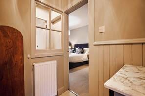 A room with a bed, a radiator, and a wooden door. - Osprey Annex family suite at Kinclune Estate, Angus (Kirkton of Kingoldrum)