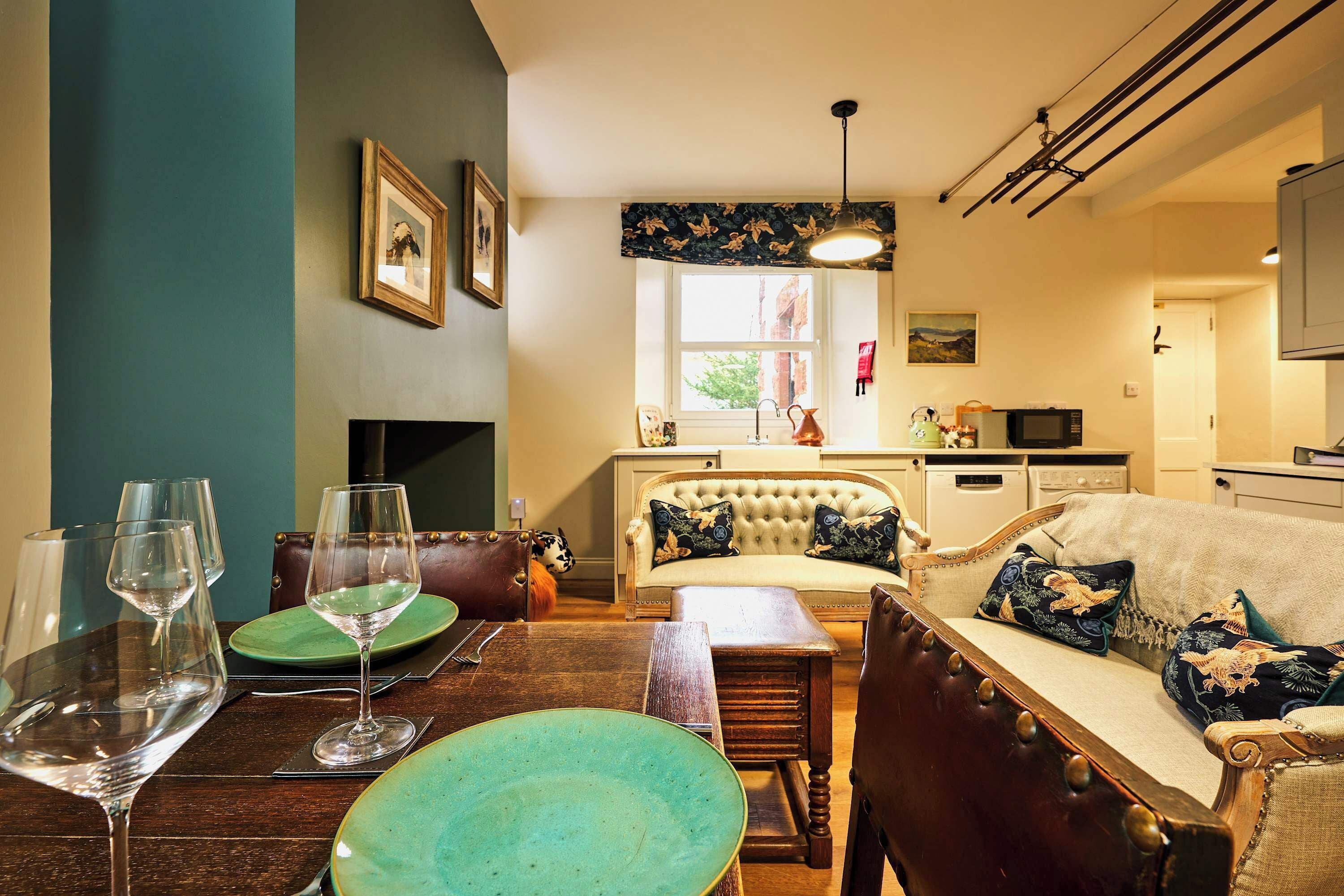 Un salón acogedor con chimenea, una mesa de comedor dispuesta con copas de vino y un sofá con cojines decorativos.