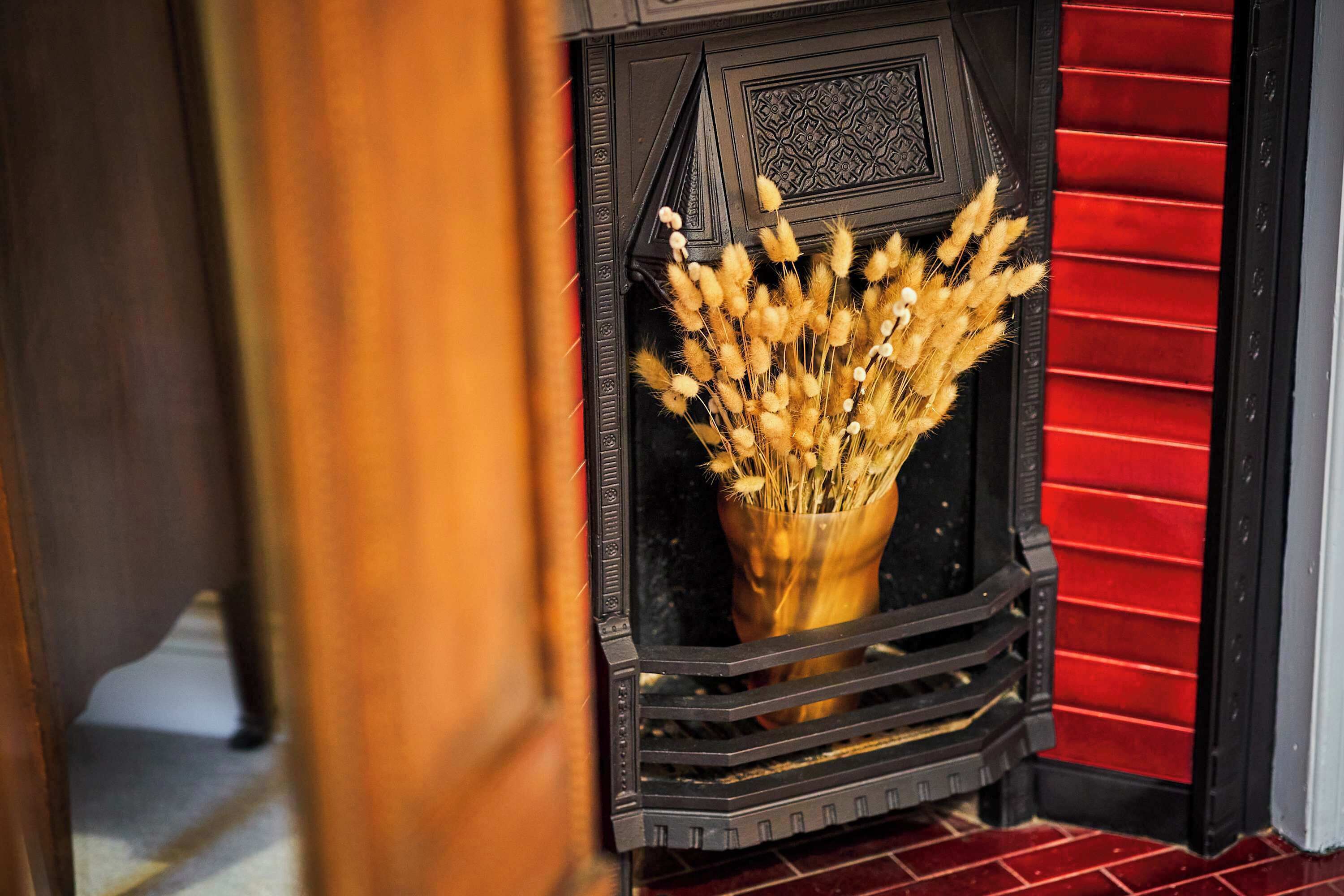 Une cheminée agrémentée d’un vase décoratif contenant des fleurs séchées.