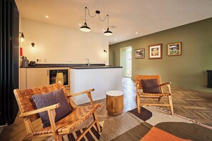 A modern kitchen with white cabinets, a black countertop, and a built-in island. There are two wooden chairs with cushions, a round wooden stool, and a patterned rug on the floor. - Barn Conversion at Kinclune Steading, Angus Glens (Kirkton of Kingoldrum)