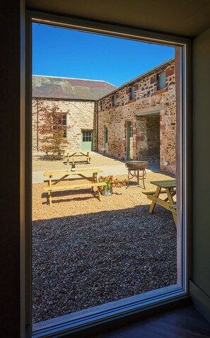 A stone building with a gravel courtyard, outdoor seating, and a barbecue grill. - Barn Conversion at Kinclune Steading, Angus Glens (Kirkton of Kingoldrum)