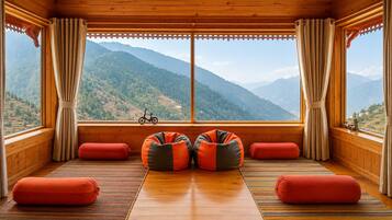 A room with a wooden floor, large windows, and a view of mountains.