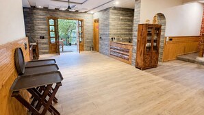 Una habitación amplia con techo alto, ventilador de techo y aparador de madera con puertas de cristal.