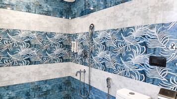A bathroom with a shower, toilet, and a towel dispenser.
