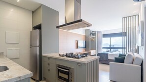 A modern kitchen with a built-in gas stove, oven, and stainless steel appliances. - Full Studio With Ocean View Vpd0603 (Florianópolis)