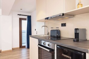 Eine moderne Küche mit Edelstahlkochfeld, integriertem Backofen, Kaffeemaschine und Wasserkocher.