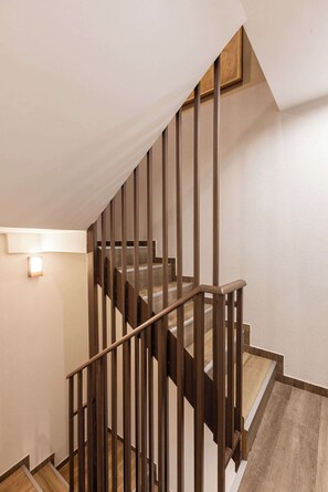 Eine Holztreppe mit Handlauf und einer Wandleuchte.